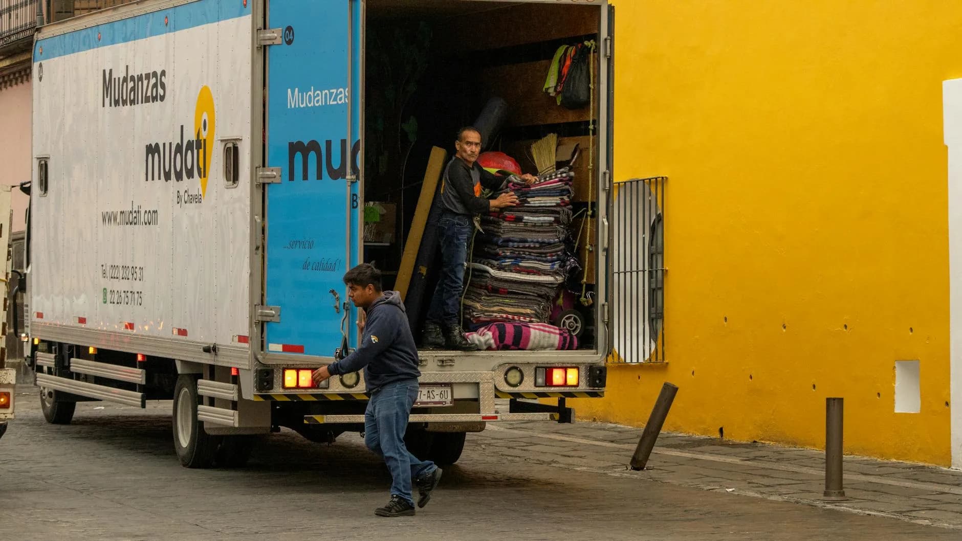 Déménageurs professionnels chargeant des cartons dans un camion de déménagement devant un immeuble